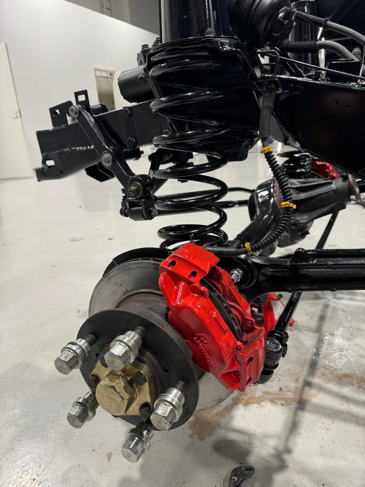 Red Brembo-style brake caliper, fresh coil spring, hub assembly